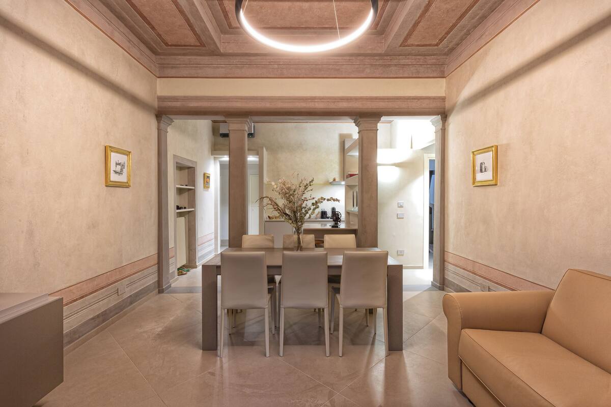A dining area with a table set for four, a sofa, and framed pictures on the walls.