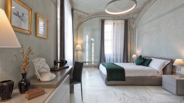 A modern hotel room with a large bed, a desk with a chair, a vanity with a mirror, and a window with curtains. - Casa del Sarto (Florence)
