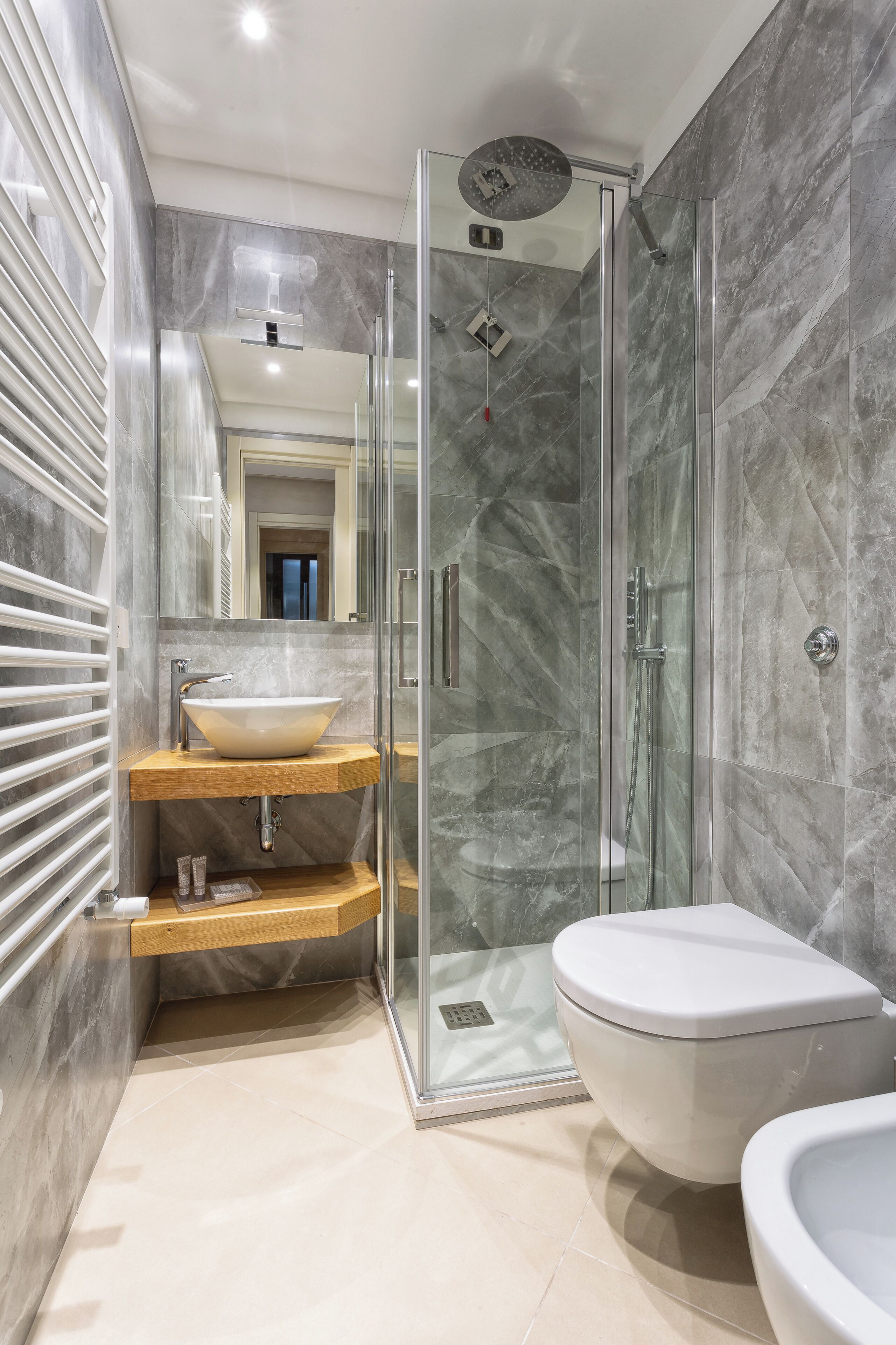 A modern bathroom with a glass-enclosed shower, a vessel sink, and a toilet.