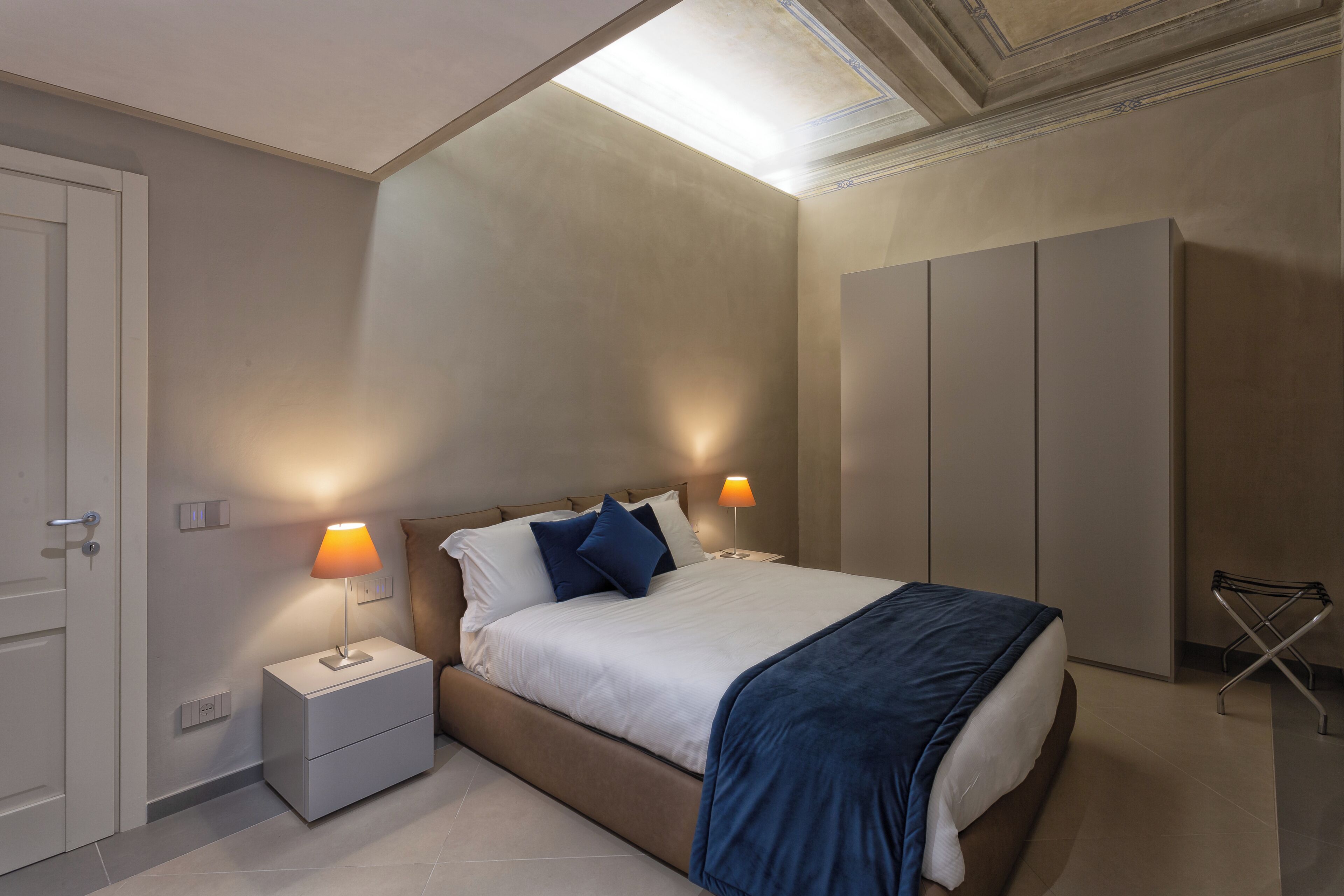 A modern bedroom with a bed, nightstands, and a wardrobe.