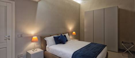 A modern bedroom with a bed, nightstands, and a wardrobe.