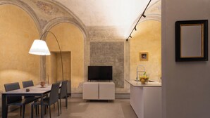 A dining area with a table and chairs, a television, and a kitchen area with a sink and countertop. - Casa del Sarto (Florence)
