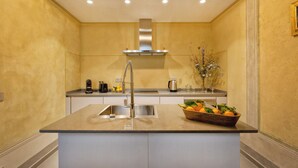 A modern kitchen with a central island, stainless steel sink, and a built-in range hood. - Casa del Sarto (Florence)