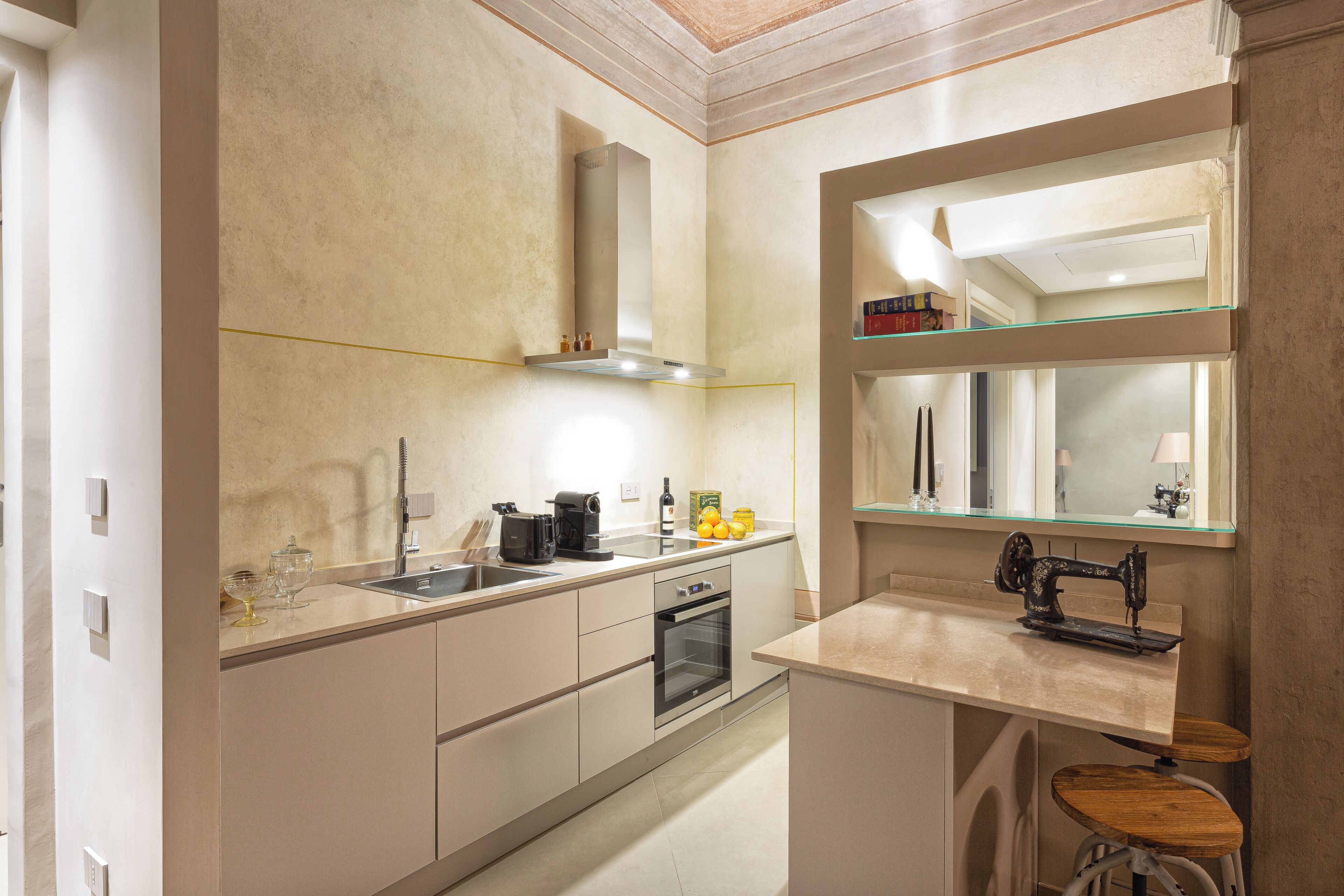A modern kitchen with a built-in oven, a sink, and a sewing machine.