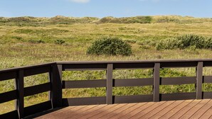 Una terraza de madera con vistas a una colina cubierta de hierba.