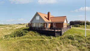 Una casa con techo de tejas rojas, paredes blancas y un muelle de madera.