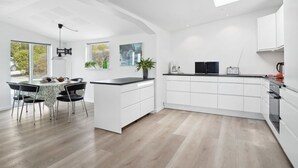 Una cocina moderna con armarios blancos, encimera negra y un tragaluz.