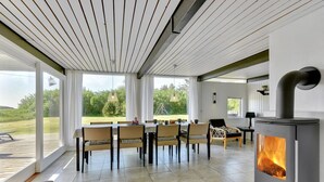 A spacious room with a large dining table, chairs, a sofa, and a wood-burning stove. - "Anund" - 1.4km from the sea by Interhome (Ringkøbing)