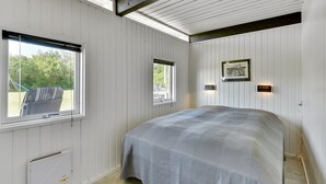 A bedroom with a bed, two windows, a radiator, and a wall-mounted light fixture. - "Anund" - 1.4km from the sea by Interhome (Ringkøbing)