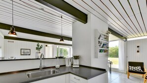 A modern kitchen with white cabinets, a black countertop, and pendant lighting. There is a window providing natural light and a view of the outdoors. - "Anund" - 1.4km from the sea by Interhome (Ringkøbing)