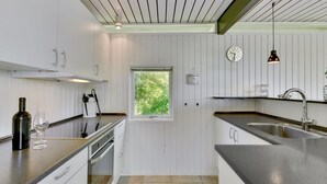 A modern kitchen with white cabinetry, a central island, a window, and a built-in oven. - "Anund" - 1.4km from the sea by Interhome (Ringkøbing)