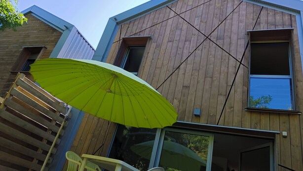 A modern building with a wooden facade, large windows, and a green umbrella. - 3 Bedroom Private vacation home in Blanquefort (Blanquefort)