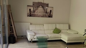 A living room with a white sofa, a glass coffee table, and a dining table with chairs. A ladder is leaning against the wall, and a painting of a bridge is on the wall. - 3 Bedroom Private vacation home in Blanquefort (Blanquefort)