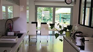 A modern kitchen with white cabinets, a built-in oven, and a large window overlooking a green garden. - 3 Bedroom Private vacation home in Blanquefort (Blanquefort)