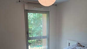A bedroom with a bed, pillows, a window with a view of greenery, and a ceiling light. - 3 Bedroom Private vacation home in Blanquefort (Blanquefort)