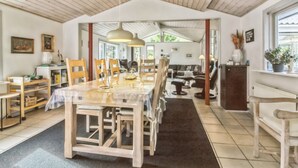 A spacious dining area with a large table, wooden chairs, and pendant lighting.