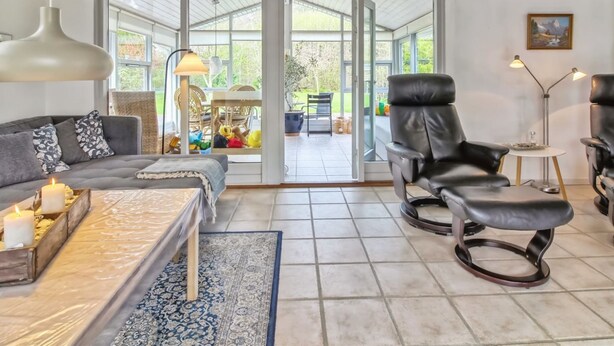 A modern living room with a sofa, two leather chairs, a coffee table, and a floor lamp.
