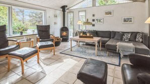A cozy living room with a fireplace, comfortable seating, and large windows.