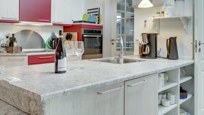 A modern kitchen with red and white cabinetry, a large island with a sink, and a coffee machine.