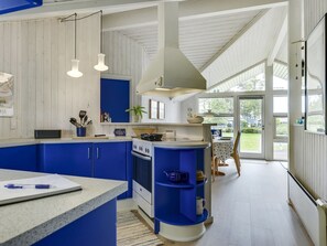 Een koelkast, een oven, een vaatwasser, kookgerei, borden en bestek