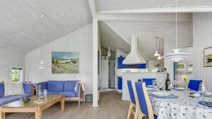 Ein großzügiger Wohnbereich mit einem blauen Sofa, einem Holztisch und einem Esstisch für sechs Personen mit blauen Stühlen.