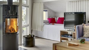Ein gemütliches Zimmer mit Kamin, einem Bett mit roten Kissen, einem Fernseher und einer Essecke.