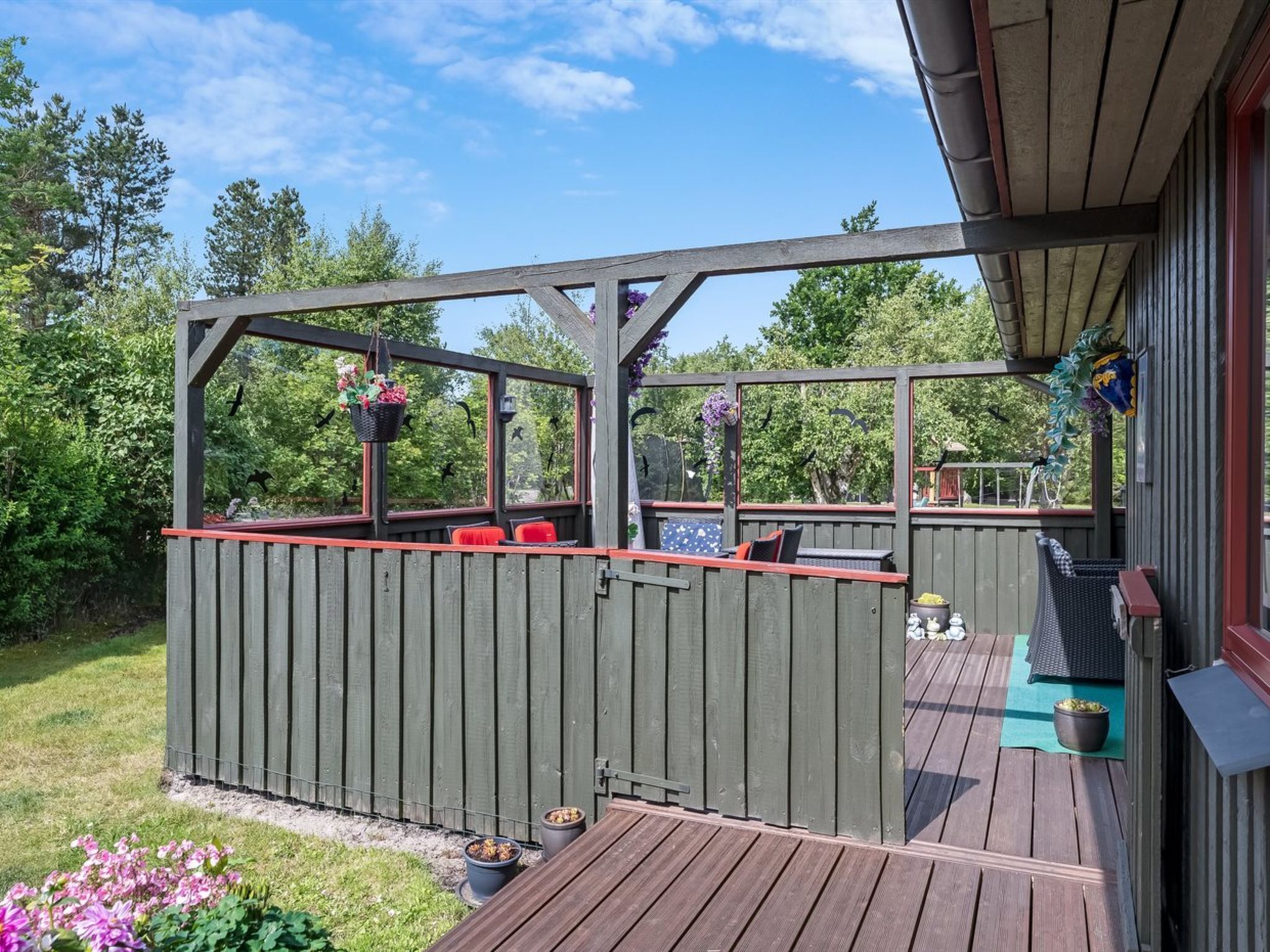 Eine Holzterrasse mit Geländer, Sitzgelegenheiten und Pflanzkübeln.