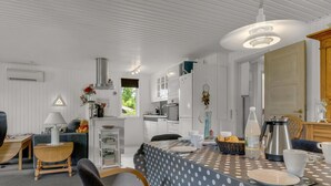 A modern kitchen with white cabinetry, a dining area with a polka dot tablecloth, and a cozy seating area with a sofa and chairs.