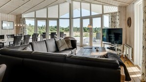 A spacious living area with a large black leather sofa, a dining table with chairs, and a television. - "Eljas" - 200m to the fjord by Interhome (Fur)