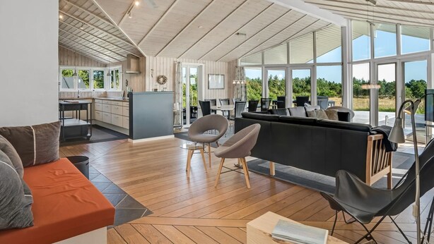 A spacious living area with a large window, a ceiling fan, and a kitchen in the background. - "Eljas" - 200m to the fjord by Interhome (Fur)