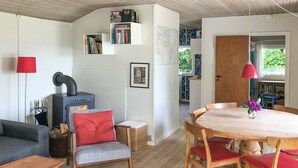 Een gezellige woonkamer met een open haard, een eettafel met stoelen en een boekenkast.