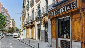 A street view with a building labeled "LECHERIA 16" featuring a wooden facade, large windows, and balconies. - Limehome Madrid Calle de la Paloma (Madrid)