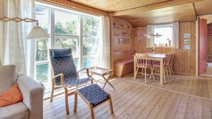 Een gezellig cabin interieur met een houten plafond, een bank, een eettafel met stoelen en een bankje.