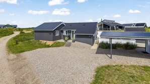 Un quartier résidentiel moderne où les maisons se distinguent par leurs toits sombres, leurs panneaux solaires et leur allée gravillonnée.