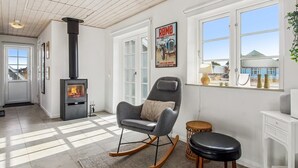 Un salon moderne avec une cheminée, un fauteuil à bascule, une petite table et une vue sur l’extérieur.