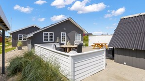 Une maison moderne dotée d’un patio, d’une table à manger et d’une table de pique-nique.