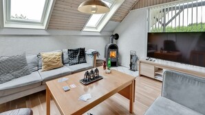 Une chambre de style loft moderne, dotée de fenêtres de toit, d’une cheminée, d’un canapé et d’une table à manger.