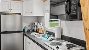 A compact kitchen with a stainless steel refrigerator, a coffee maker, and a microwave.