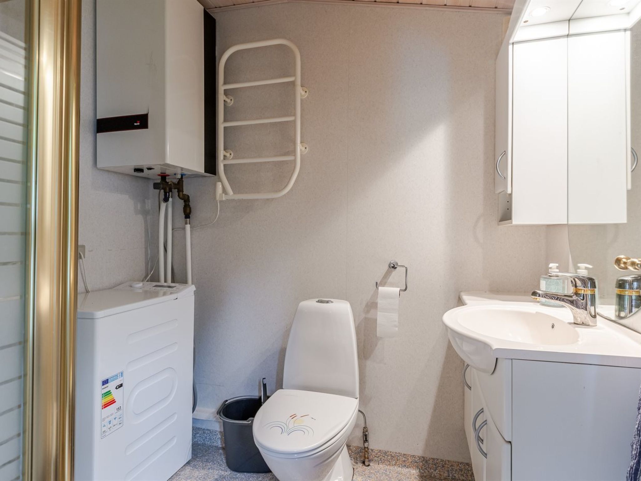 A compact bathroom with a toilet, bidet, sink, and a small trash bin.
