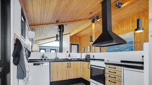 Una cocina moderna con armarios de madera, una estufa grande e iluminación colgante.