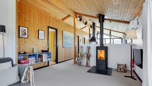 Interior acogedor de una cabaña con paredes de madera, una chimenea, un sofá y un televisor.