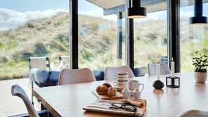 Un comedor moderno con una mesa de madera, sillas y vistas al exterior.