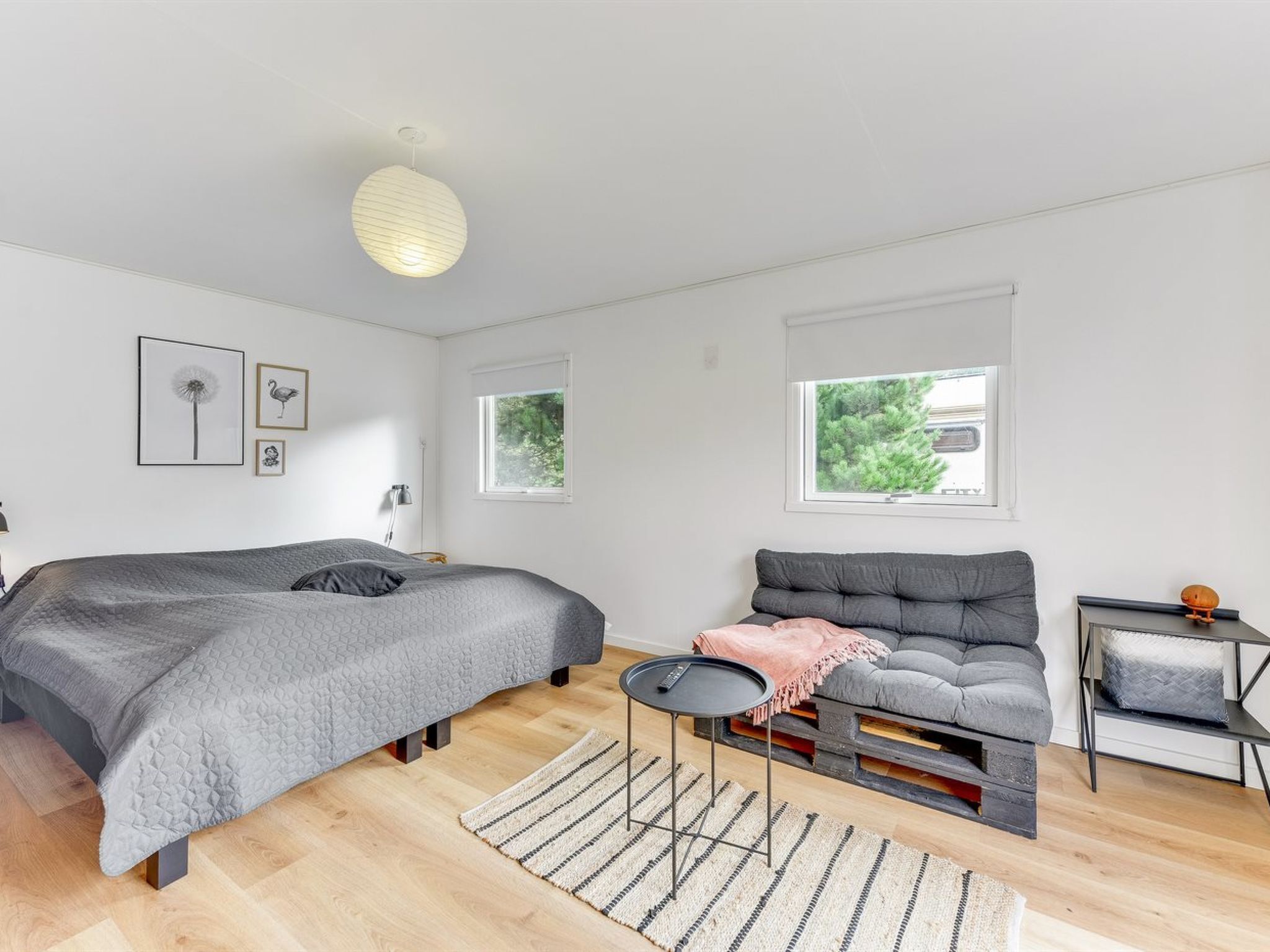 Un dormitorio moderno con cama, sofá, una mesita y una ventana.