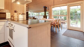 Una cocina moderna con una isla central, techo de madera y ventanas amplias con vistas al exterior.