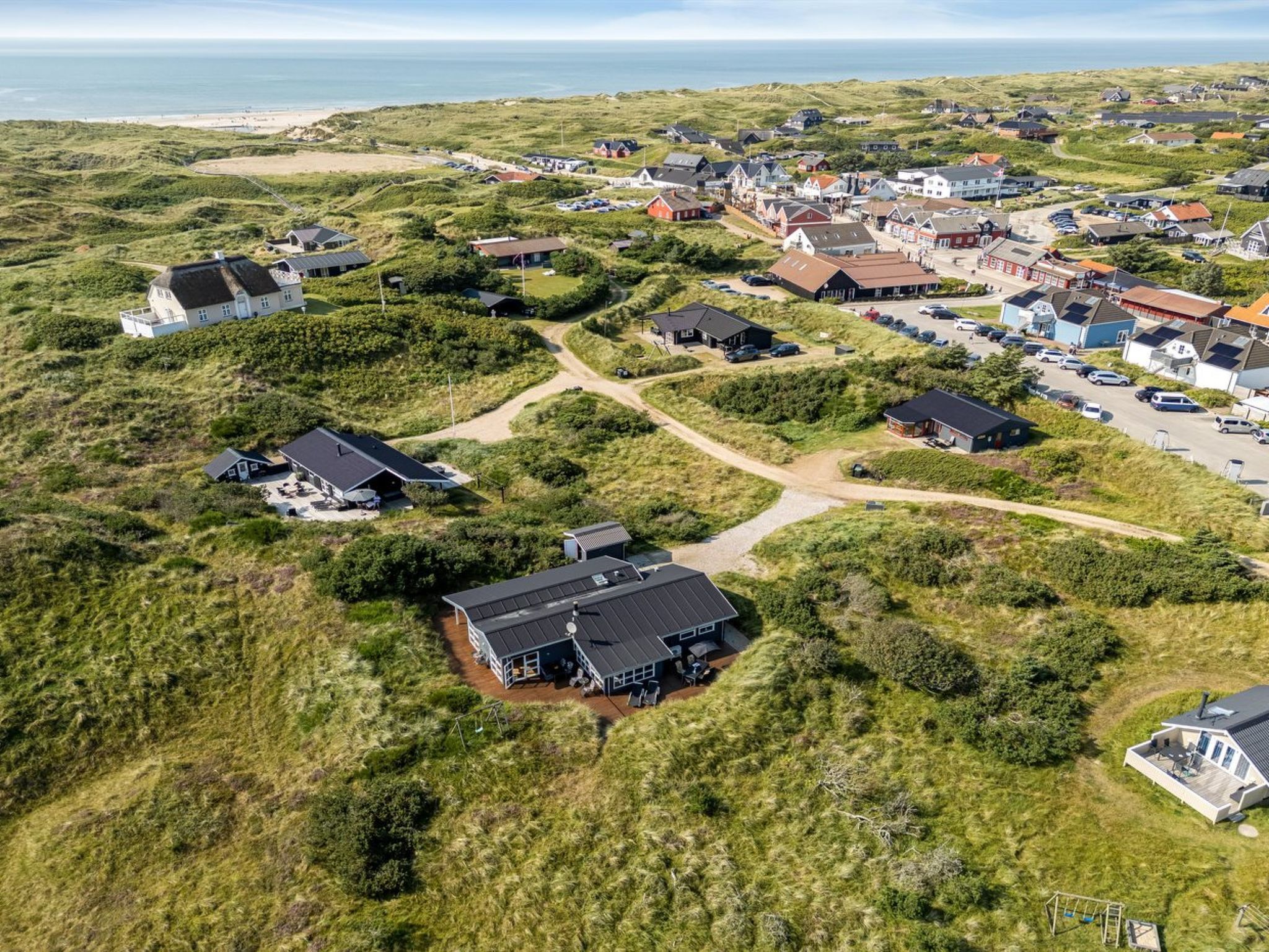 Vue aérienne d’un village côtier avec des maisons, une plage et une route.