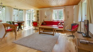 A spacious living room with a wooden ceiling, a red sofa, a dining table with chairs, and a television. - "Eina" - 250m from the sea by Interhome (Hals)