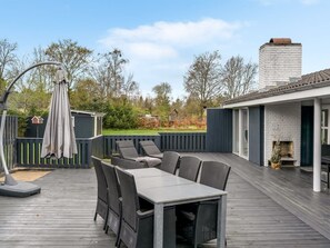 Een terras met een tafel en stoelen, een schoorsteen en een omheinde tuin.