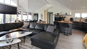 Ein modernes Wohnzimmer mit einem schwarzen Ledersofa, einem weißen Couchtisch und einer Küchenzeile mit Barbereich.
