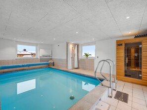 A swimming pool with a view of the outside, a sauna area, and a window with a view of the outside.