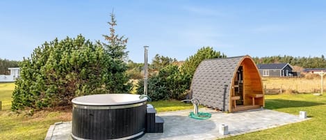 A hot tub and a wooden structure in a landscaped outdoor area.
